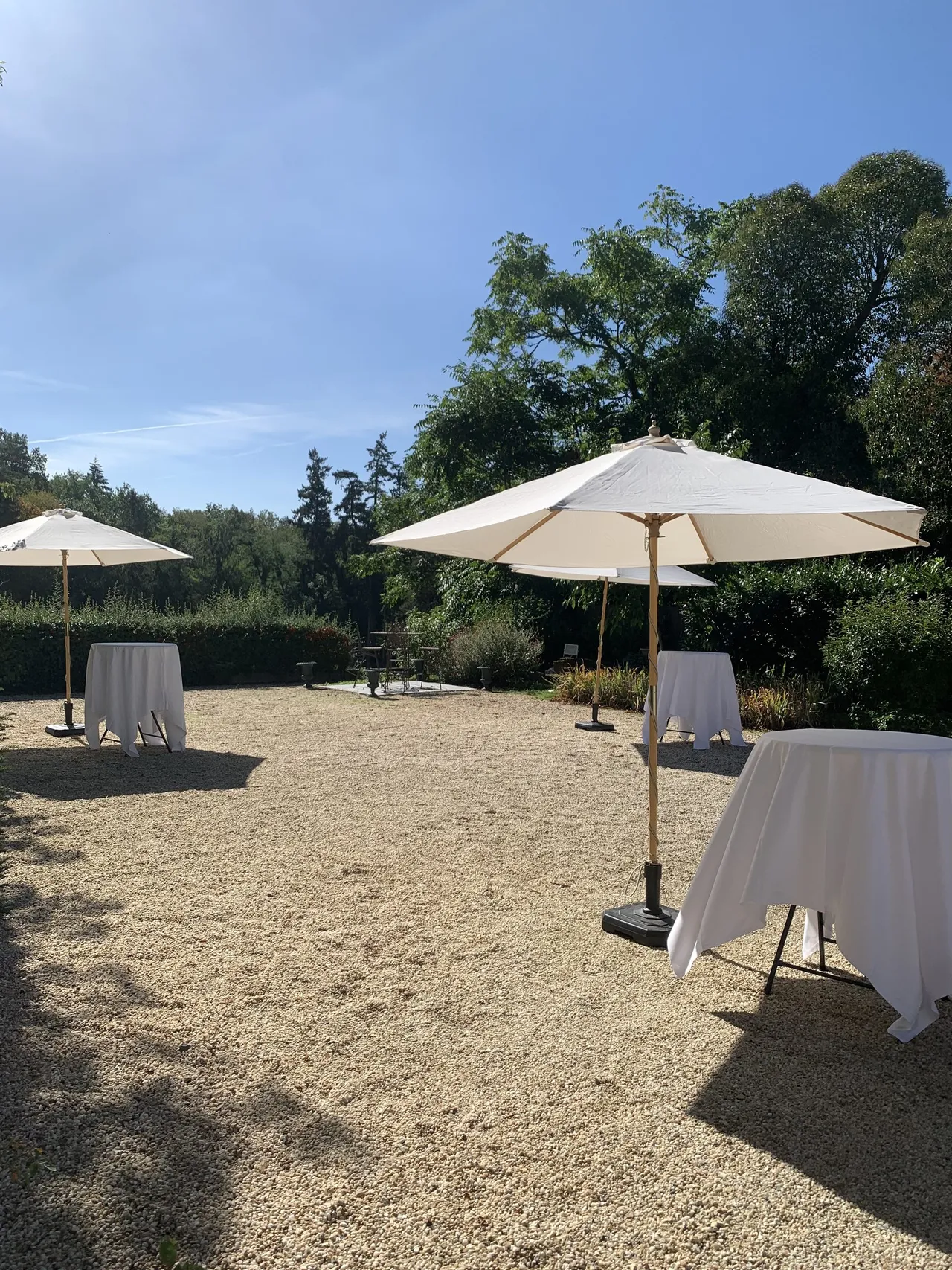 Parasols blancs et mange-debout pour un cocktail dans la cour