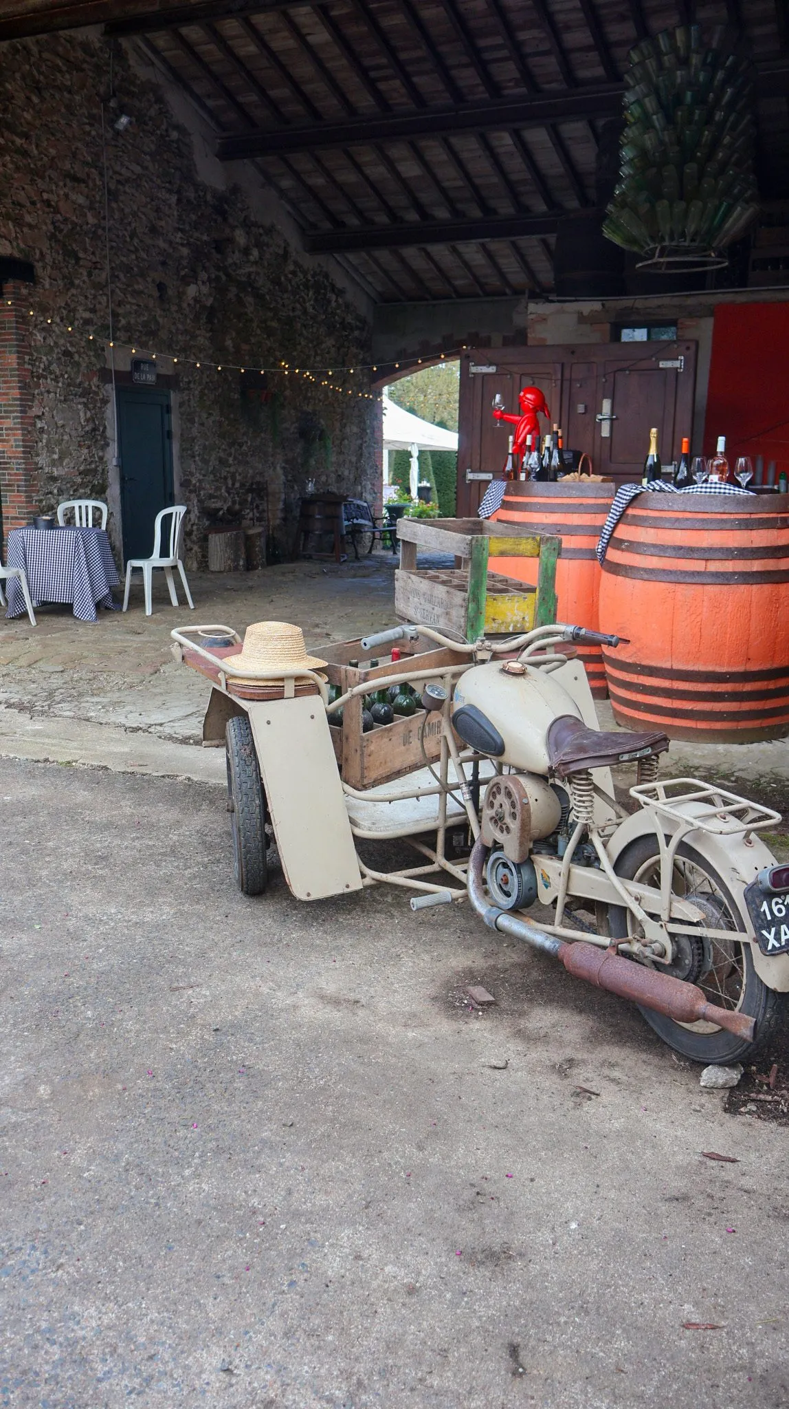 Moto ancienne et tonneaux sous le porche décoré