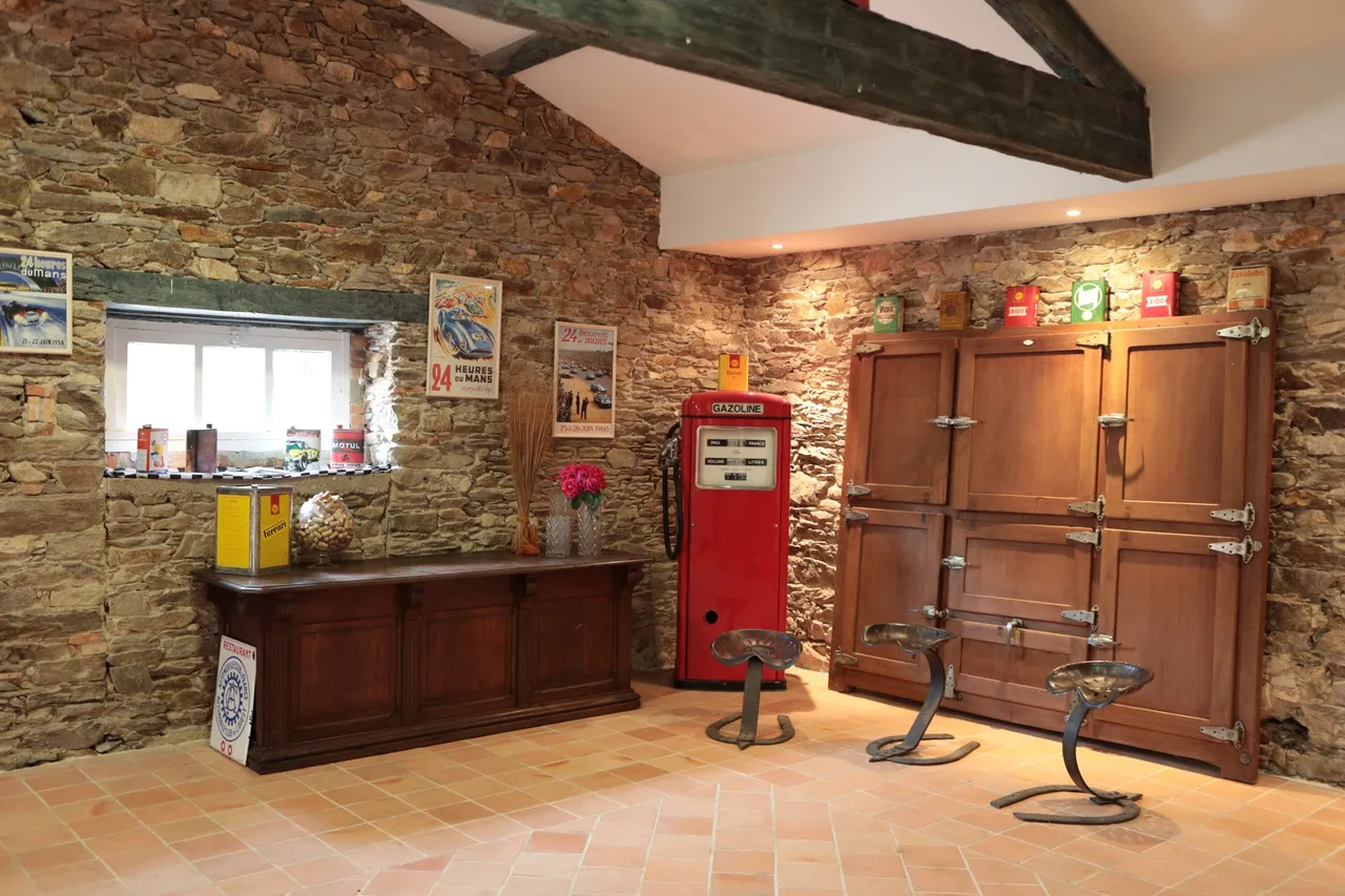 Coin bar avec armoire ancienne et pompe à essence vintage contre un mur de pierre