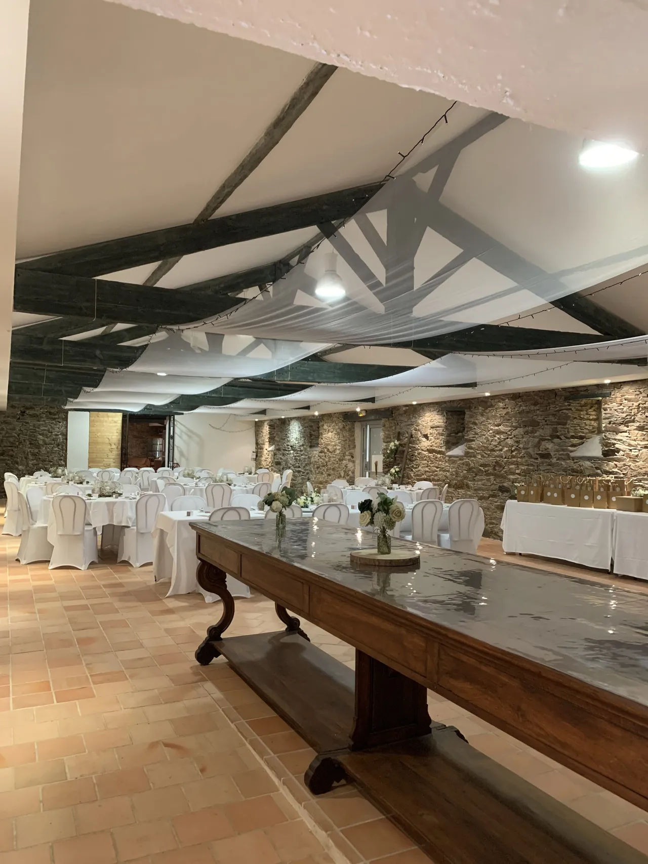 Longue table en bois dressée dans la salle de réception sous la charpente
