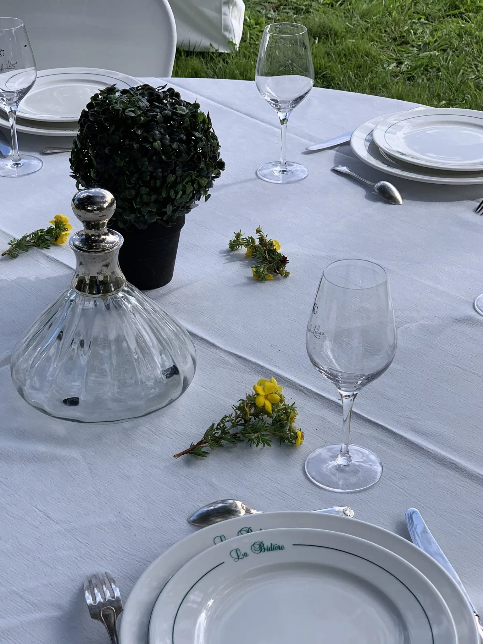 Table dressée avec carafe en cristal, verres et fleurs jaunes