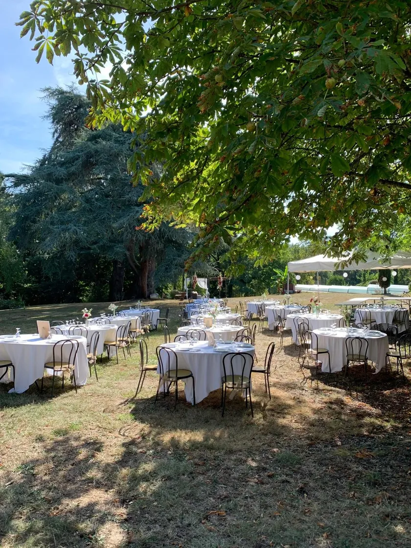 Tables rondes dressées à l’ombre des arbres du parc